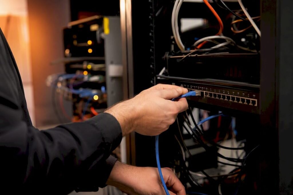 Hands securing network cable in small IT closet